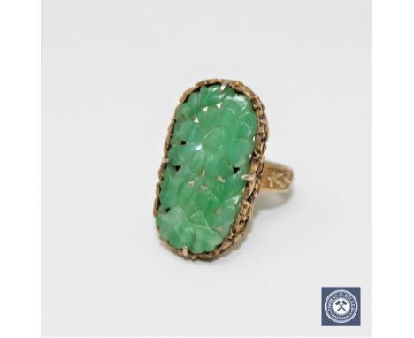 A Chinese silver gilt carved jade ring CONDITION REPORT: 7.0g. In good condition. There is a maker's mark to the shank. 
