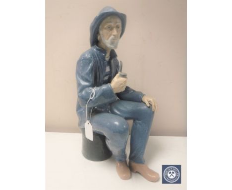 A Nao figure of a fisherman seated smoking a pipe, in matt finish, height 38cm