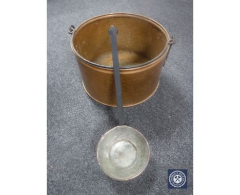 A large copper cooking pot with ladle