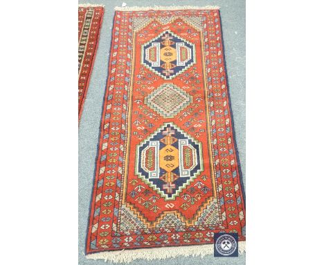 A Caucasian design runner on red ground, 190cm by 83cm