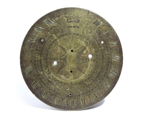 A BRASS SUNDIAL 18TH CENTURY engraved with a crowned armorial crest amongst foliage, Arabic minutes, Roman hours and months a