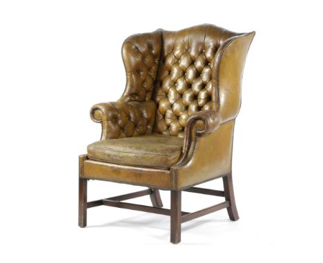 A MAHOGANY WING ARMCHAIR IN GEORGE III STYLE, 20TH CENTURY button upholstered with studded leather, on moulded front legs