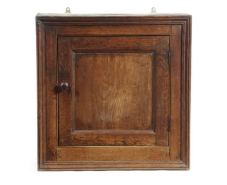 A GEORGE III OAK HANGING CUPBOARD LATE 18TH CENTURY with a panelled door enclosing a shelf 61cm high, 60.1cm wide, 27.5cm dee