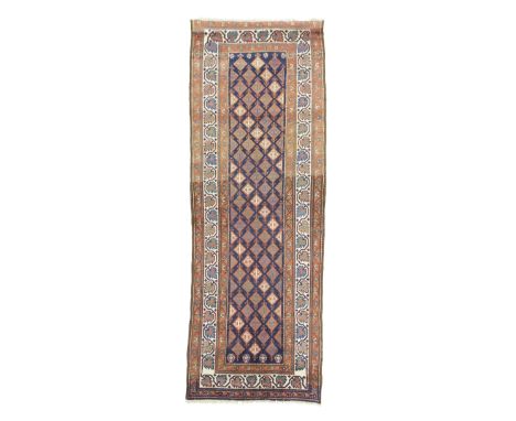 A NORTH WEST PERSIAN RUNNER C.1910 the indigo field with a diamond lattice design, enclosed by ivory borders of angular leave