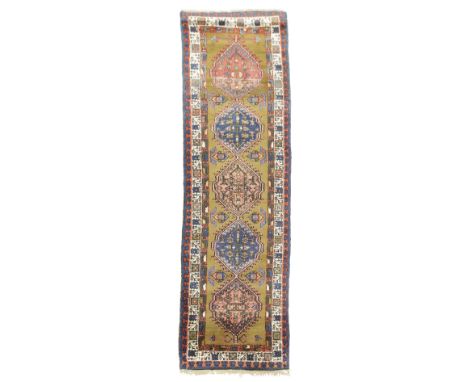 A SARAB RUNNER NORTH WEST PERSIA, C.1930 the camel field with five polychrome medallions, flanked by stylised flowers, enclos