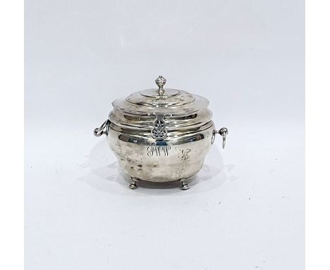 George V silver tea caddy of circular bulbous form with hinged cover and ring handles, raised on pad feet, Birmingham 1915, h