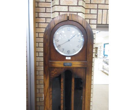 An Art Deco oak Longcase Clock with arched top, circular dial and weight chiming mechanism with glazed panelled door.