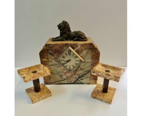 An Art Deco style marble mantle clock with lion to top and a pair of garnitures height 34 cm.