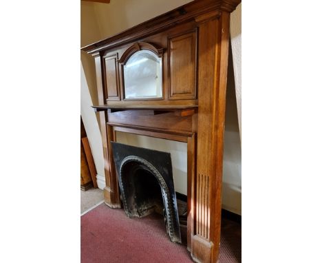 An early 20th Century solid oak, raised back mirrored and panel fire surround, fluted column sides and cast iron fire insert 