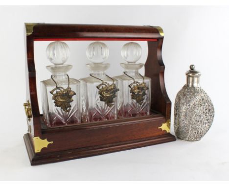 Mahogany three bottle tantalus, locked and a white metal overlay dimple decanter