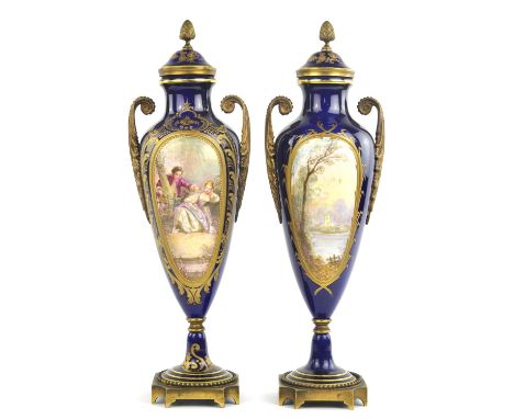 A pair of Sevres style porcelain vases, early 20th century, with 18th century figural scenes and gilt brass handles and squar