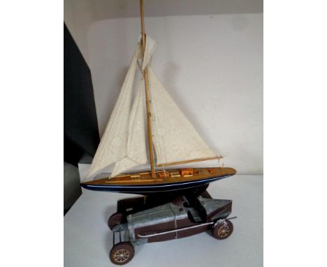 A wooden model of a yacht together with a contemporary tin plate vintage racing car  