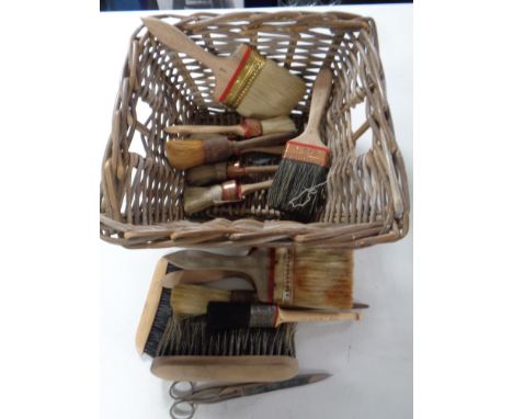 A wicker basket containing a quantity of assorted vintage paintbrushes 