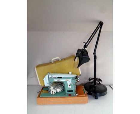A 20th century New Home electric sewing machine in case together with an angle poise magnifying lamp 
