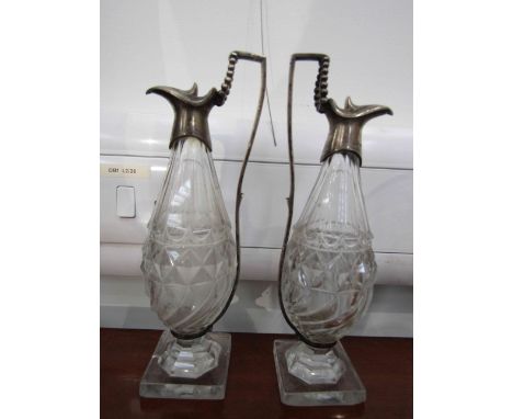 A pair of silver mounted glass oil and vinegar ewers, bird beak sports, right angled handles, cut glass body on lemon squeeze