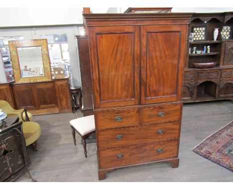 A George III flame mahogany gentleman's wardrobe, the two doors opening to reveal tray space, over two short and two long dra
