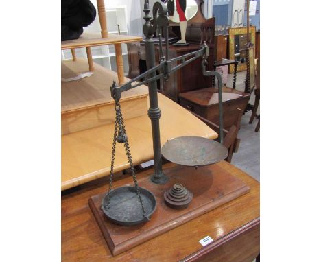 A set of weighing scales with weights, on wooden plinth