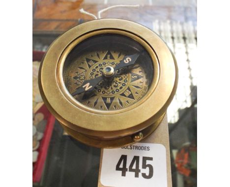 A circular brass compass with magnifying glass 