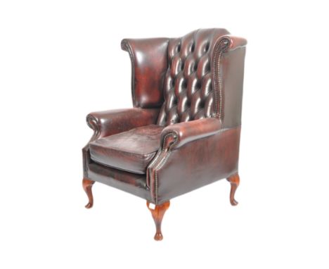 A 20th Century Queen Anne revival burgundy leather Chesterfield wingback armchair raised on cabriole legs with pad feet. The 