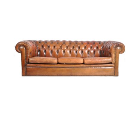 A 20th Century tan brown leather Chesterfield button backed three seater sofa settee having scrolled arms and backrest with b