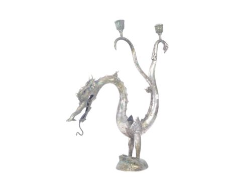 An early 20th century Thai silver plated candlestick holder in the form of a dragon with back raised stood upon two feet with