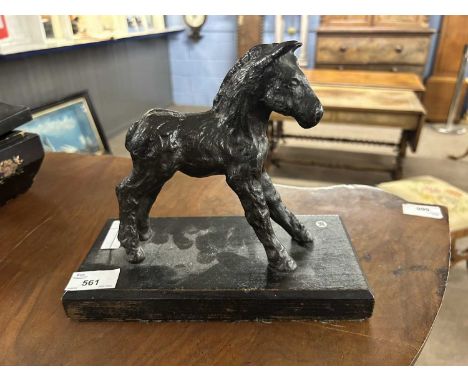 A bronzed finish iron model of a foal on an ebonised wooden base, 24cm long max