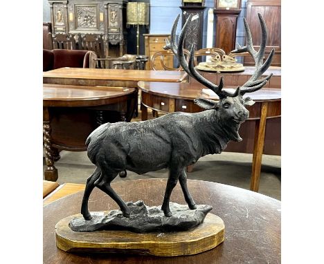 A black painted iron model of a stag set on wooden base, 47cm high