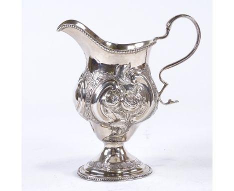 A Victorian silver helmet-shaped cream jug, relief embossed floral and foliate decoration with bead edge border and gilt inte