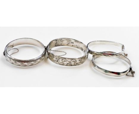 Two silver and foliate engraved bangles, each on a snap clasp with safety chain, a faceted silver bangle, and a further bangl