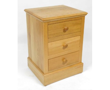 A light oak bedside chest, of three drawers, raised on a plinth base, 74cm high, 53cm wide, 46cm deep.