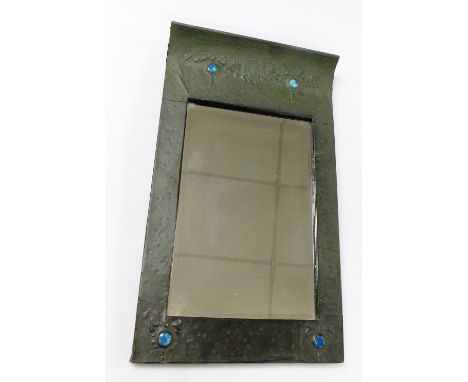 An Arts &amp; Crafts hammered pewter wall mirror, of rectangular form, with a slopped top, decorated with bows inset with Rus