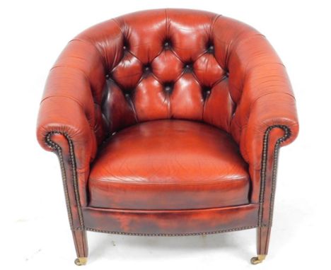 A mahogany and ox blood red leather button back armchair, raised on channelled square legs, on castors, 77cm wide.