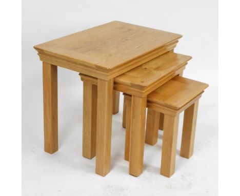 A nest of light oak occasional tables, raised on square legs, largest table 55cm high, 68cm wide, 44cm deep.