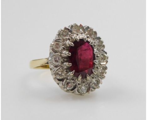 A ruby and diamond ring, the oval cut ruby and surround of diamonds, set in a white and yellow metal mount, stamped 18ct, rub
