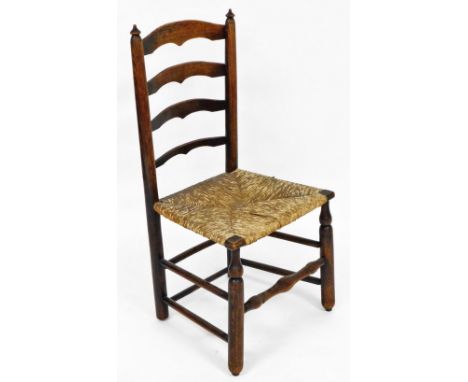 A 19thC oak ladder back chair, with rush seat, raised on cylindrical turned legs united by stretchers.