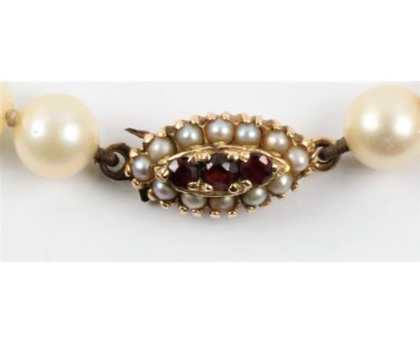 A string of cultured pearls, with a hallmarked 9ct yellow gold garnet and split pearl clasp. BOOK A VIEWING TIME SLOT ON OUR 