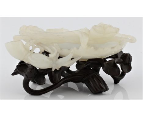A pale green jade lotus form dish on leaf carved wooden base, approx. 6cm x 12cm. IMPORTANT: Viewing is available for this lo