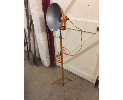 An orange industrial spot light on tripod base