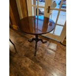 A George III style mahogany tripod table, the circular top on a gun barrel column ending in a