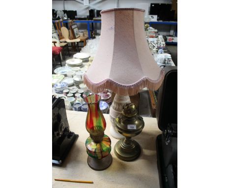 A brass oil lamp, a coloured glass similar and a table lamp and shade