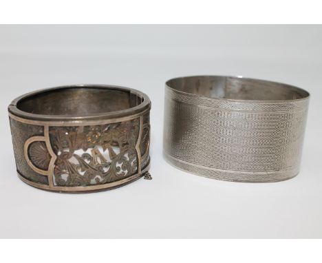 Two antique silver bangles with Birmingham marks; the first with engine turned decoration, the other with ornate, pierced dec
