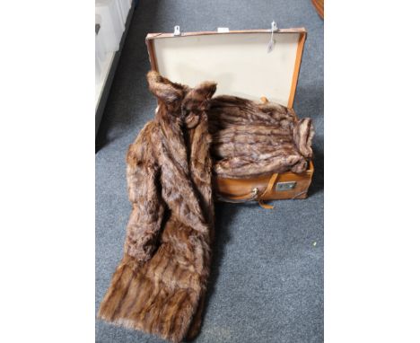 A vintage leather trunk containing three fur coats and a fur stole 