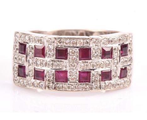 A ruby and diamond band ring, set with twelve square cut rubies, each surrounded by round brilliant cut diamonds, mounted in 