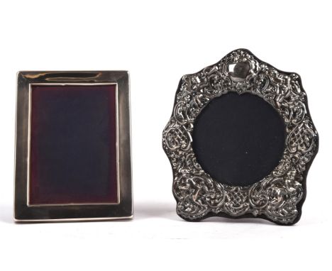 Two silver photo frames, the first embossed and with cherub decoration the second in plain form
