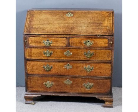 A George III oak bureau, the slope enclosing pigeon holes, central cupboard and nine small drawers, two short and three long 