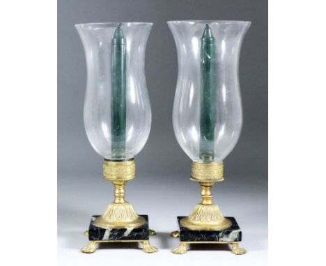 A pair of Continental gilt brass and polished marble storm candlesticks, on lion paw feet, and with bell-shaped glass shades,