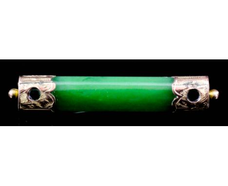 A Chinese green jade rectangular bar brooch with gold coloured metal end mounts, 2.3ins x 0.4ins  (58mm x 10mm) overall