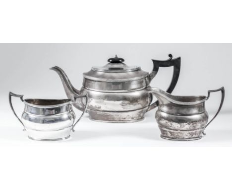 A George V silver oval three-piece tea service with reeded mounts and angular handles, comprising - teapot with ebonised hand