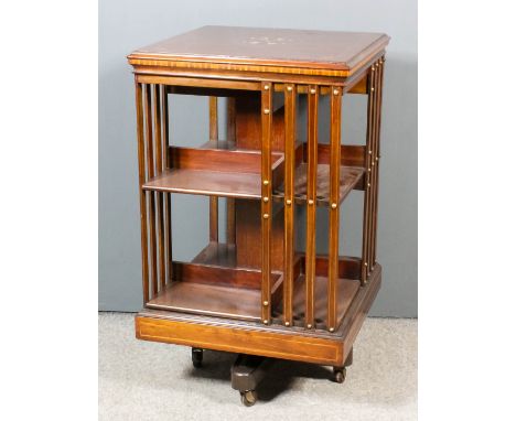 An Edwardian mahogany square revolving bookcase, the top inlaid with marquetry depicting a mythical beast and scroll ornament