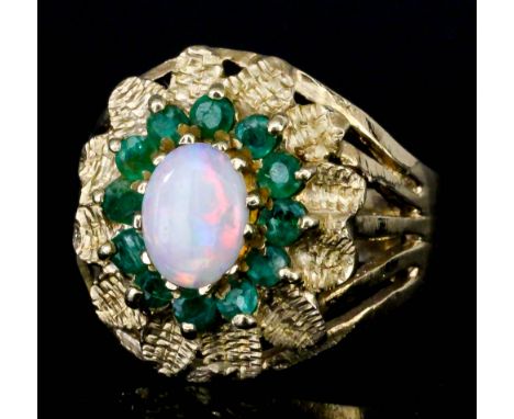 A modern 9ct gold mounted opal and emerald ring, set with central oval opal, 5mm x 7mm, surrounded by sixteen small emeralds 